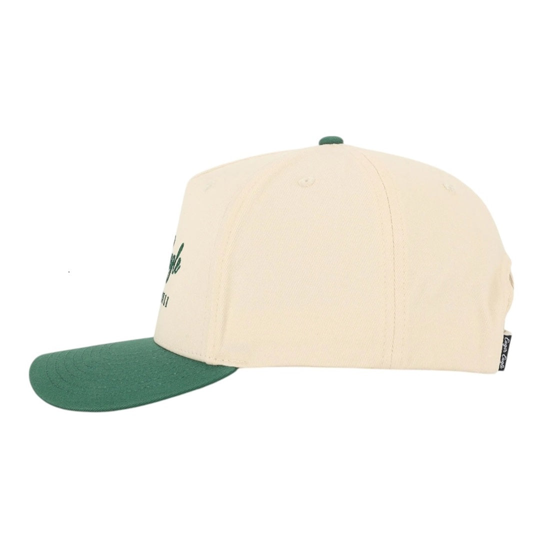 The Heritage | Golf Hat is a premium cotton cap in beige with a green brim, seen from the side. This golf hat features a small side tag and visible panel stitching.