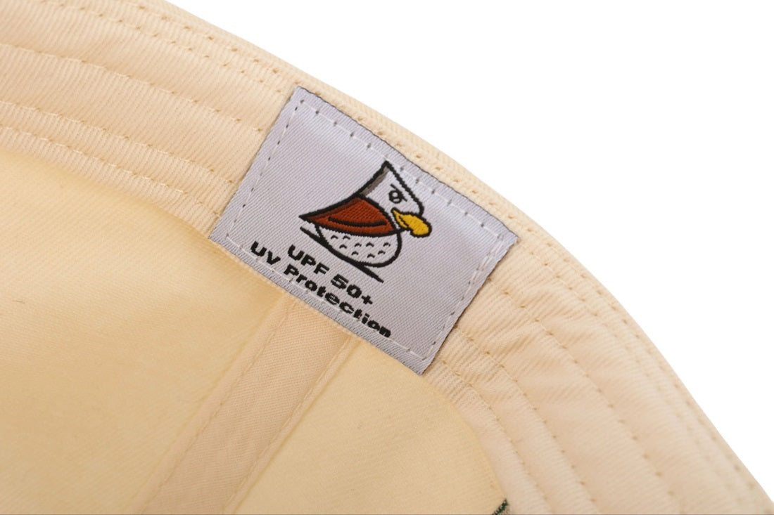 A close-up of the Heritage Black | Golf Hat with a white label featuring a cartoon bird and UPF 50+ UV Protection text—ideal for modern golfers seeking reliable sun protection on and off the course.