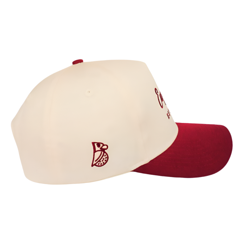 The Oxblood | Golf Hat features a cream crown, maroon brim, maroon side-stitched logo, and partial embroidered front text. Shown from the side, this hat provides UPF50+ sun protection.