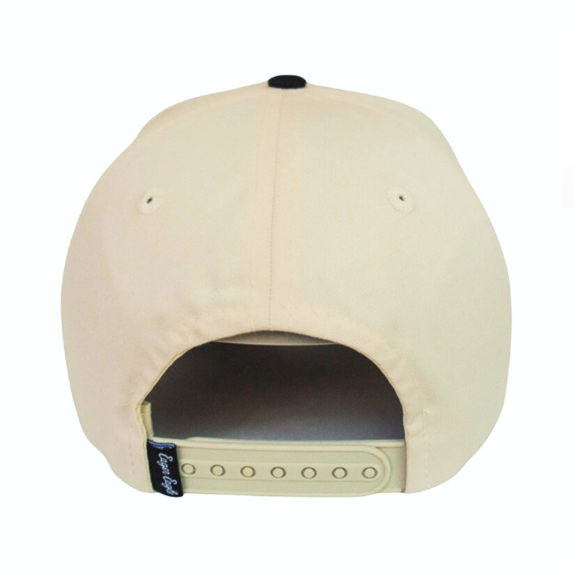 The Heritage Black Golf Hat is a beige baseball cap with an adjustable snapback strap, a small black tag on the left side, and UPF50+ sun protection—perfect for the modern golfer.